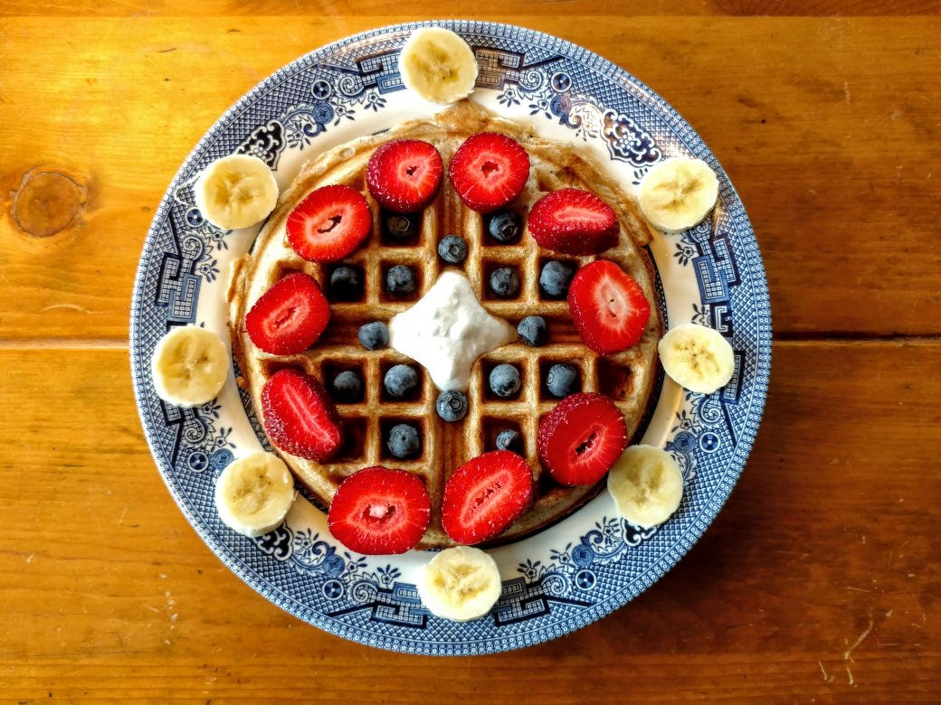 vegan sourdough waffles, overhead view, with strawberries, bananas, blueberries, and coconut cream