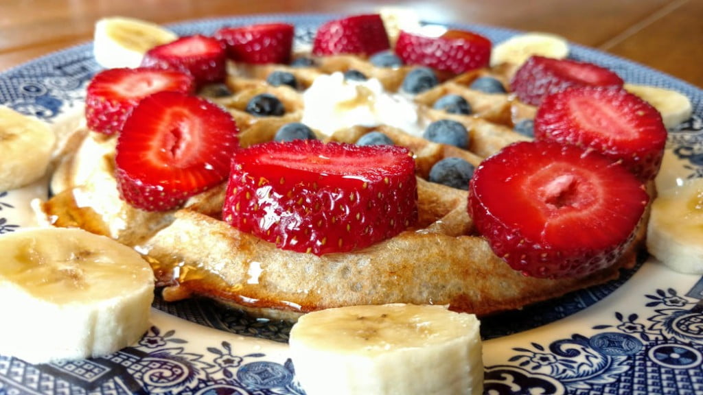 vegan sourdough waffles, side closeup view, with strawberries, blueberries, and banana
