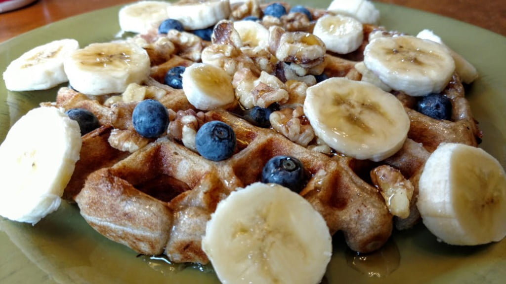 vegan sourdough waffles, side view, with blueberries, walnuts, bananas, and coconut cream